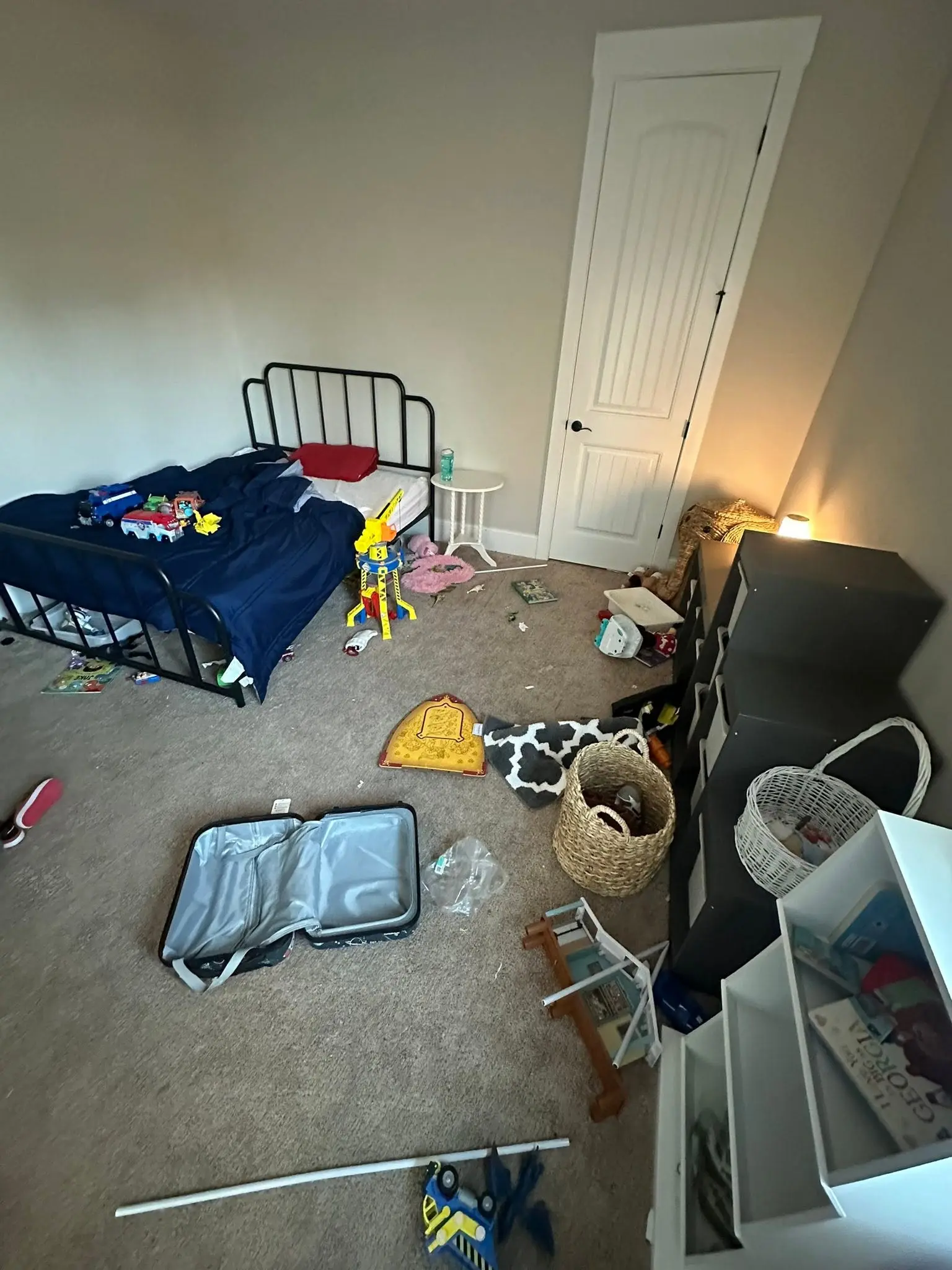 Cluttered child bedroom with toys and an open suitcase on the floor before a deep cleaning