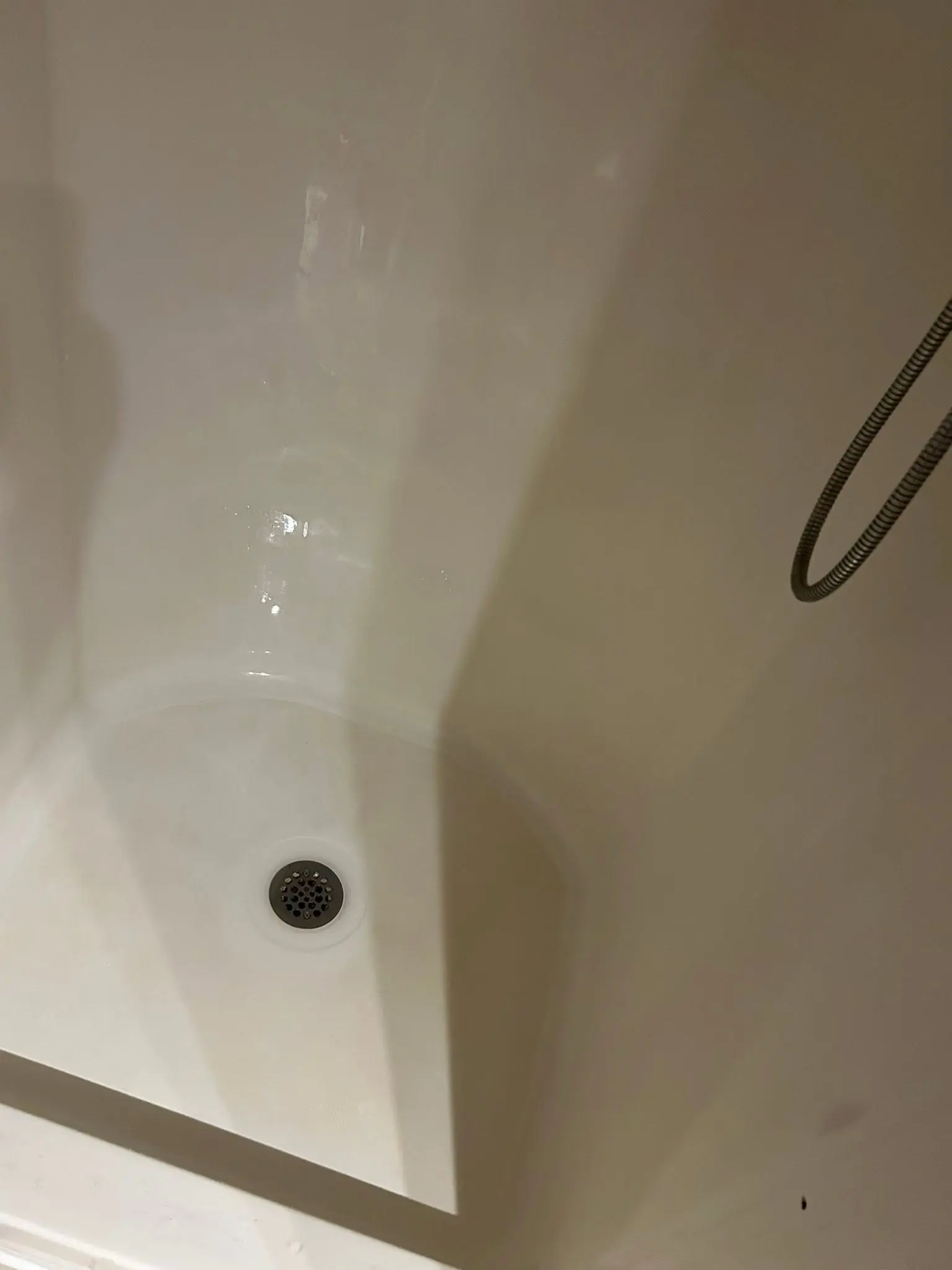Detail of a shower pan corner cleaned along the caulk line and drain