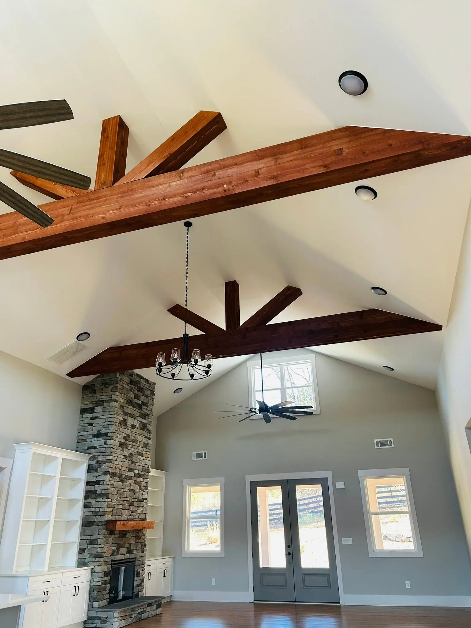 Vaulted living room with exposed wood beams and stone fireplace dusted top to bottom