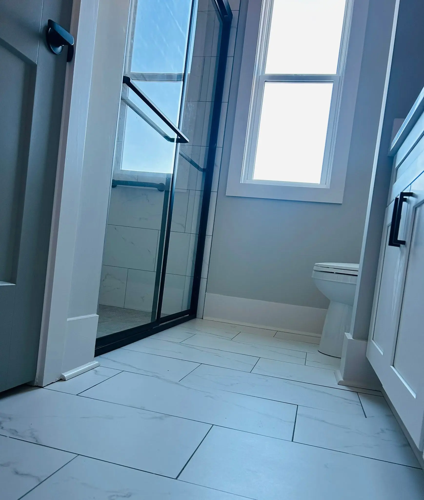 Marble tile bathroom floor and glass shower enclosure cleaned spotless