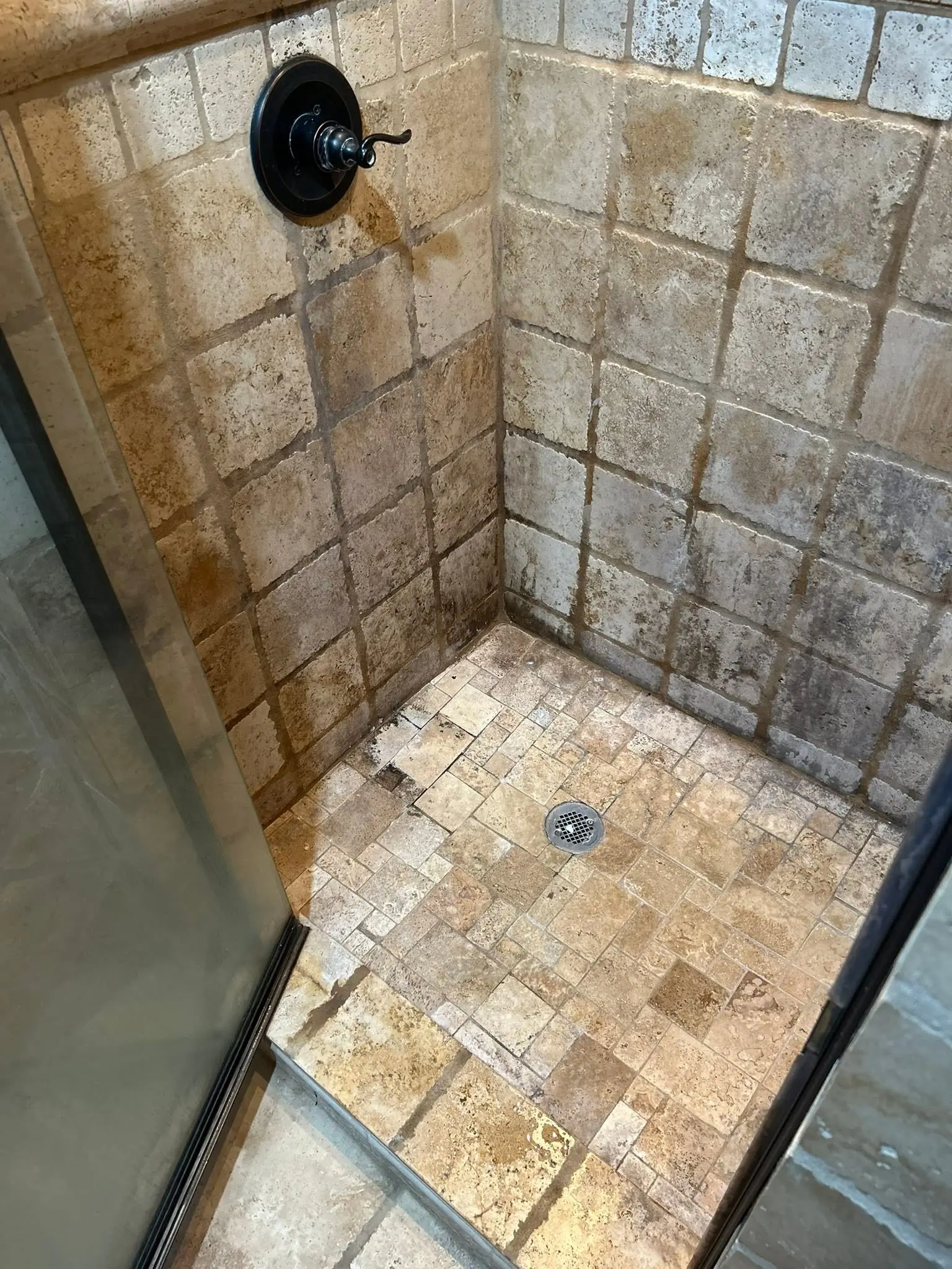 Stone tile shower corner sanitized and rinsed clear of hard water residue