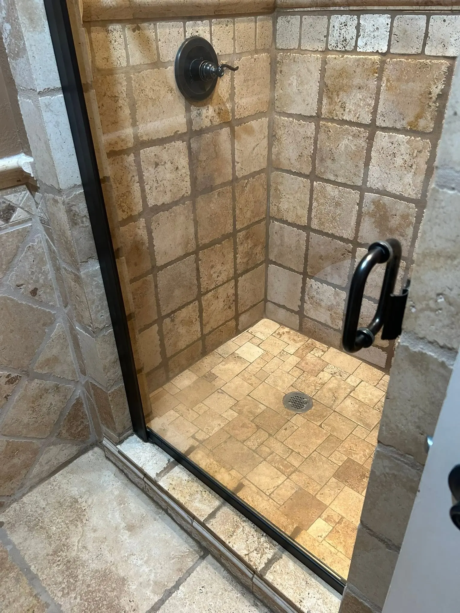 Travertine tile shower with clean stone walls and floor after a deep cleaning service